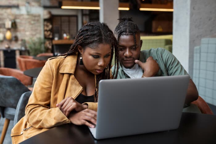 Two people working on a laptop placed on a modern table.